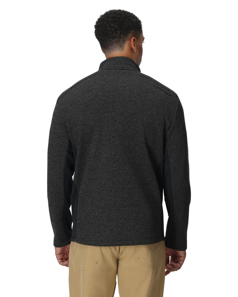 Man wearing a dark gray sweater and beige pants on a white background