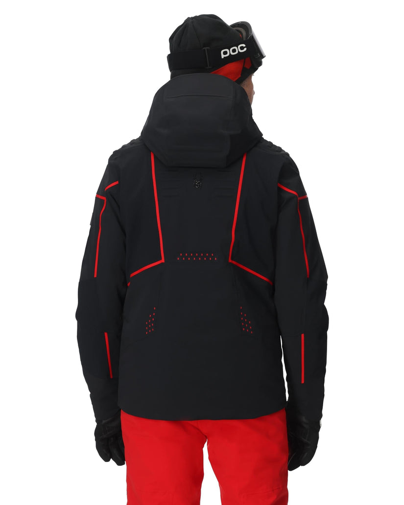 Person wearing a black jacket with red accents and red pants on a white background