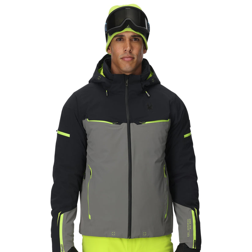 Person wearing a black and gray ski jacket with neon green accents on a white background