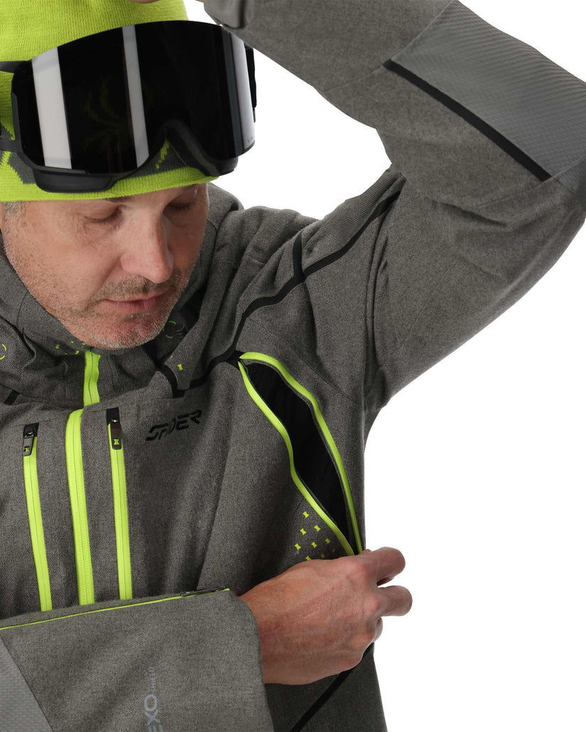 Person wearing a gray jacket with green accents and a helmet, on a white background