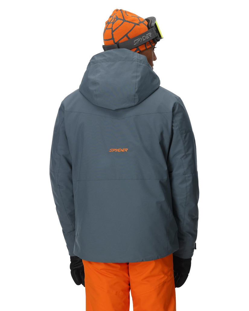 Person wearing a gray jacket with a brand logo, orange pants, and a matching orange helmet on a white background