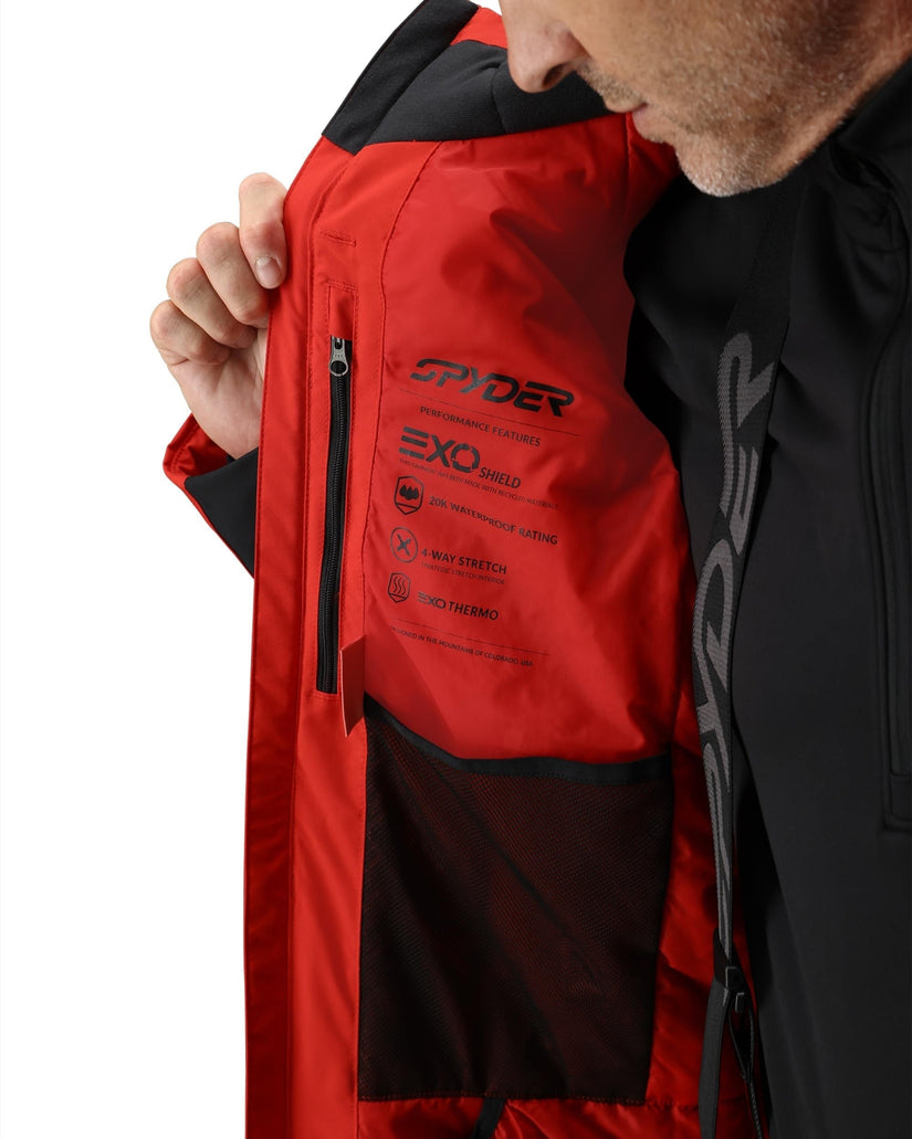 Red jacket with Spyder branding held by a person against a white background